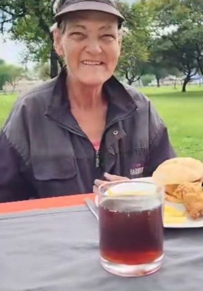 'n Vrou glimlag by die tafel met 'n koppie tee