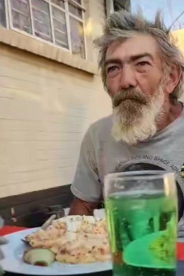 'n Man met 'n baard by die tafel met 'n bord kos